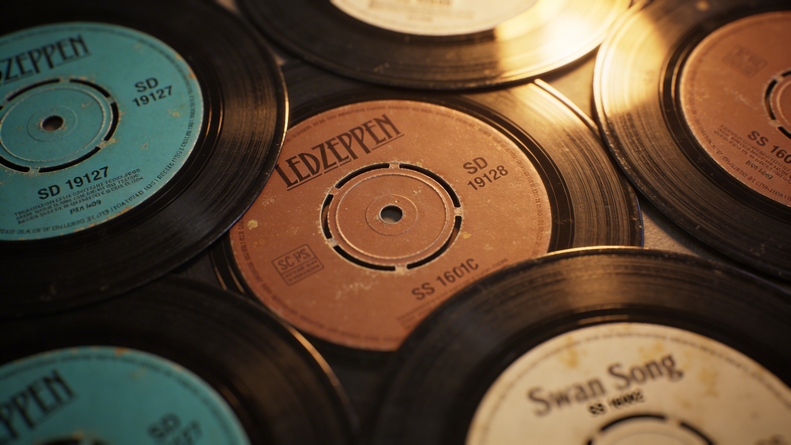 Photorealistic: Close-up of multiple Led Zeppelin first pressing labels arranged in a fan pattern, showing turquoise Atlantic, brown Atlantic, and Swan Song variations, warm incandescent lighting, sha