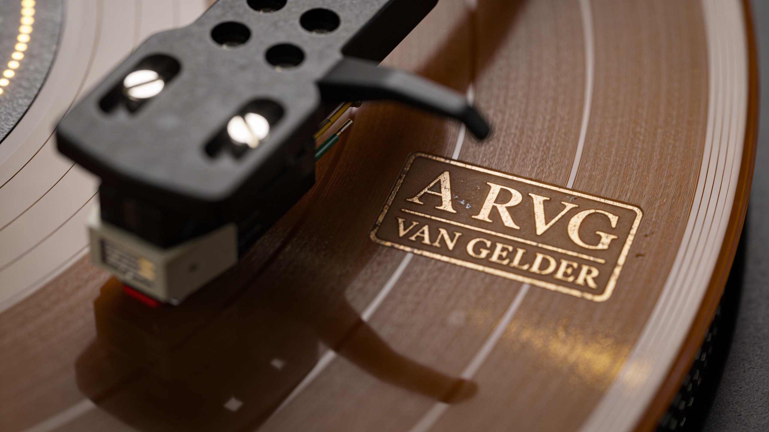 Photorealistic: Detailed close-up of Van Gelder stamp in record dead wax area, professional lighting highlighting the etched details, turntable cartridge and stylus in soft focus, technical precision 