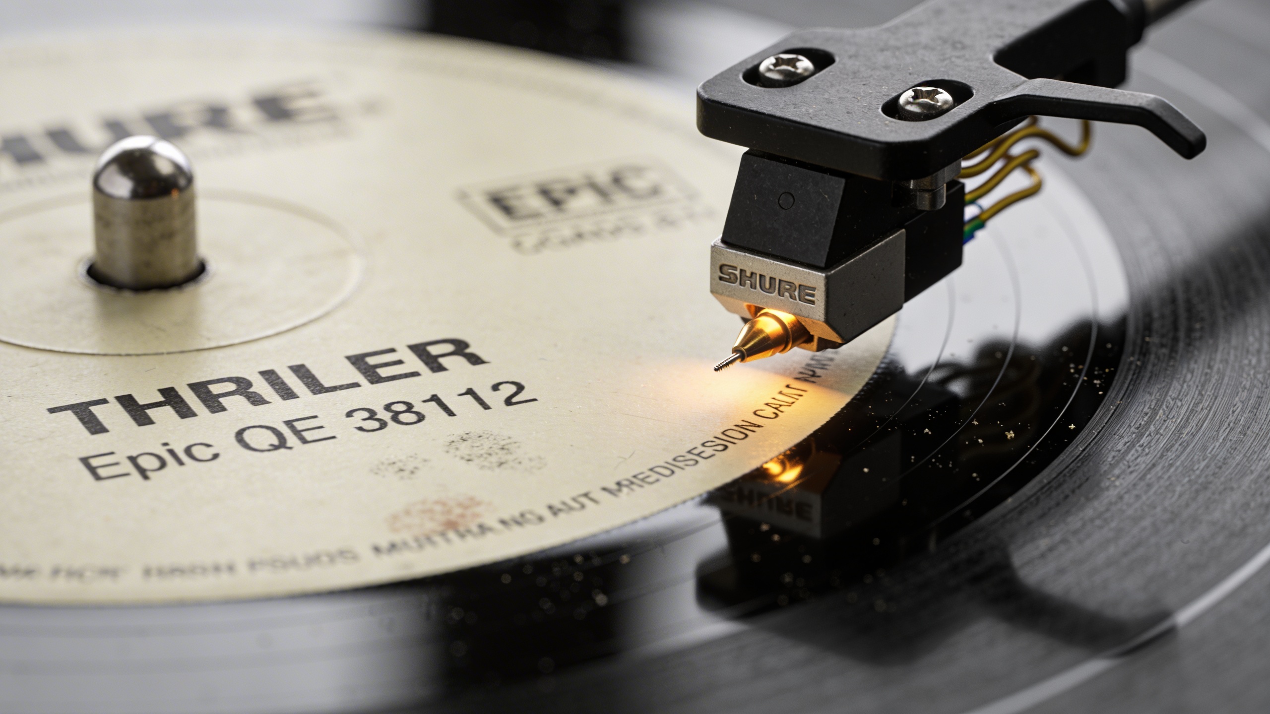 Photorealistic: Detailed macro shot of Thriller vinyl record label showing Epic catalog number QE 38112, needle approaching the groove, warm golden lighting, turntable cartridge in sharp focus, authen