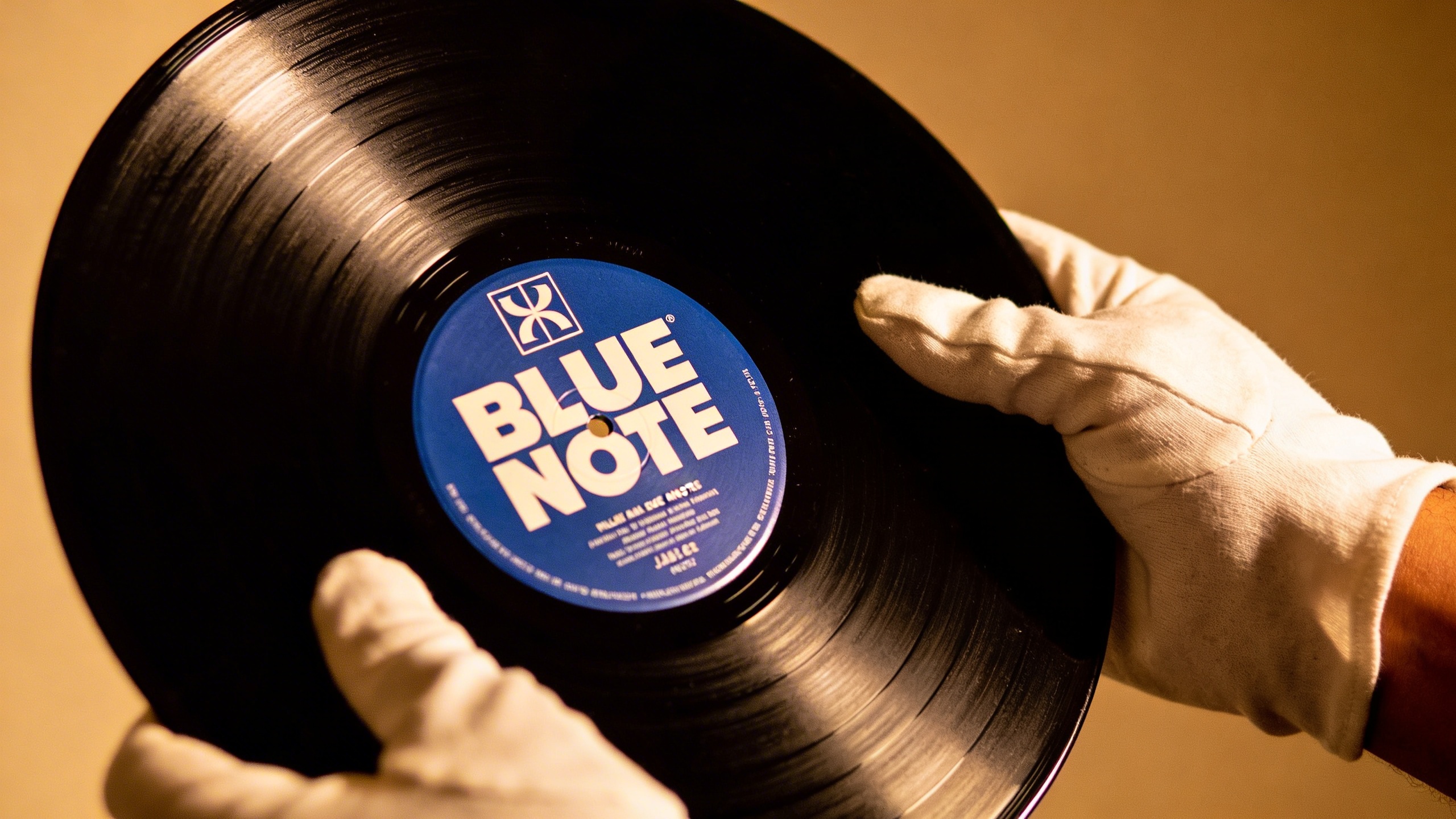Photorealistic: Hands holding a pristine Blue Note jazz album with the distinctive label visible, warm studio lighting, vintage aesthetic, focus on the iconic typography and label design, collector's 