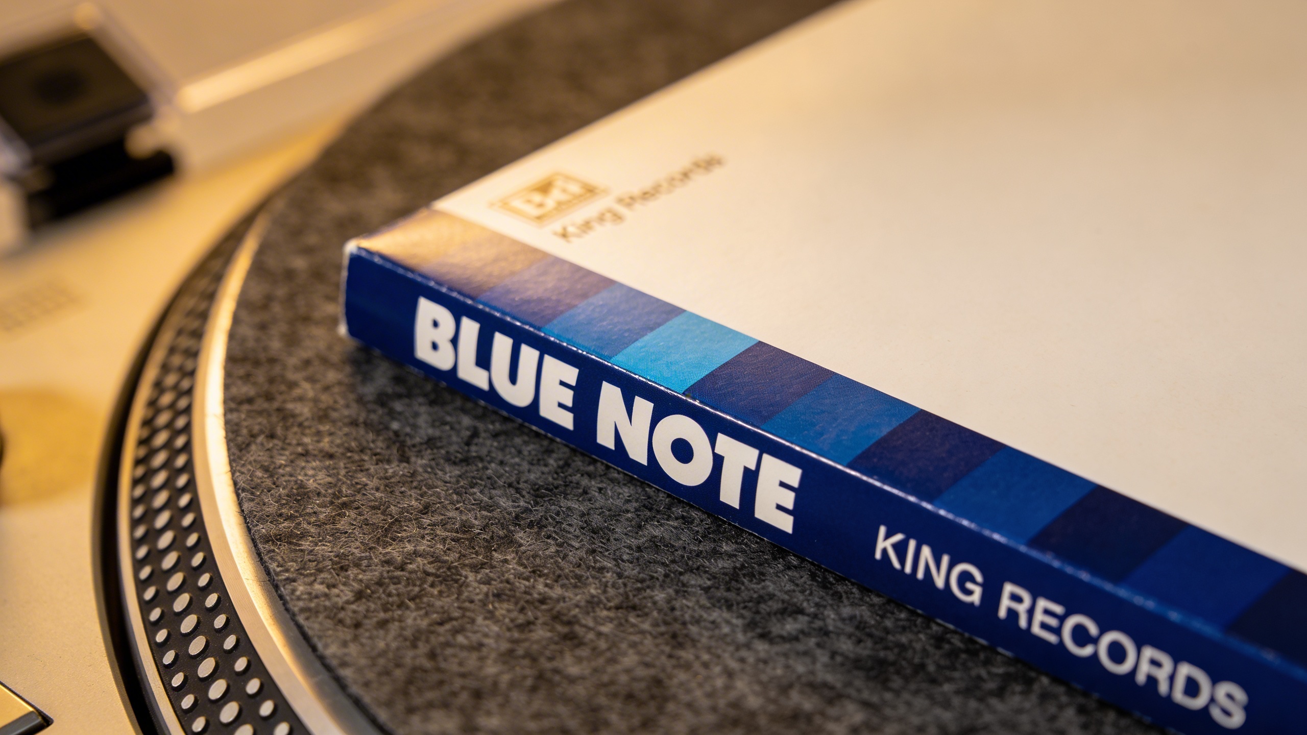 Photorealistic: Japanese King Records Blue Note reissue with obi strip, laid flat on felt turntable mat, pristine condition with sharp corners, soft studio lighting highlighting the obi's typography a